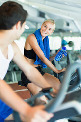 Couple using exercise machines in gym - CUF01371