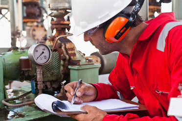 Arbeiter notiert Messgerät in Ölraffinerie - CUF01385