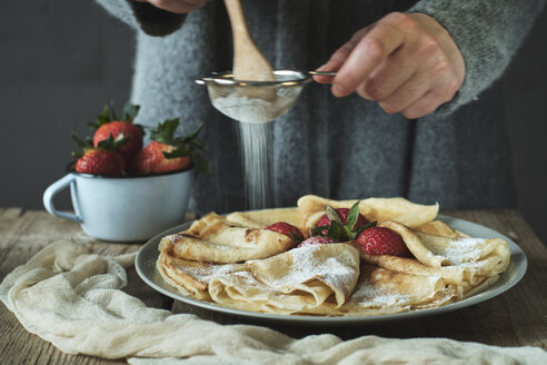 Woman preparing pancakes with strawberries for breakfast - BZF00389