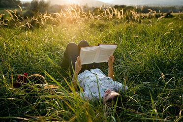 Woman lying in grass reading - CUF01459