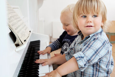 Two boy toddlers sitting at a piano - CUF01478