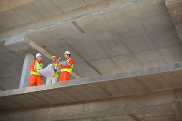 Arbeiter, die auf der Baustelle Baupläne lesen - CUF01533