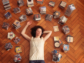 Woman lying on floor, listening to music - CUF01551