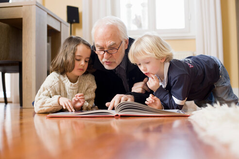 Alter Mann liest Kindern ein Buch vor - CUF01552
