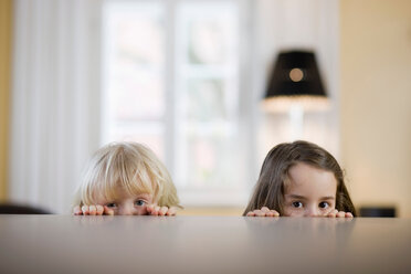 Children looking over table edge - CUF01553