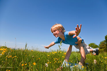 Vater und Sohn spielen auf einem Feld mit einem Flugzeug - CUF01600