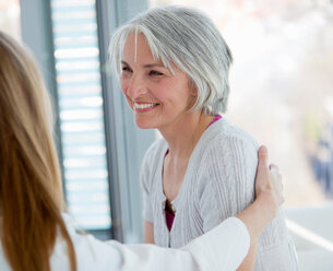 Doctor hugging smiling woman in office - CUF01615