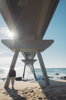 Mann steht entspannt unter einer Brücke am Strand - SKCF00449