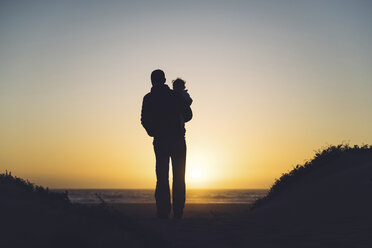 USA, Kalifornien, Morro Bay, Silhouetten von Vater und Baby genießen den Sonnenuntergang am Strand - GEMF01932