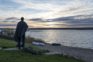 Mann steht am Seeufer bei Sonnenuntergang - PAF01841
