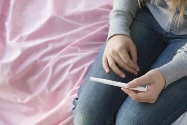 Ein Mädchen im Teenageralter hält einen Schwangerschaftstest - ISF00201