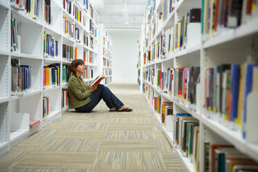 Junge Frau sitzt auf dem Boden einer Bibliothek - CUF01824