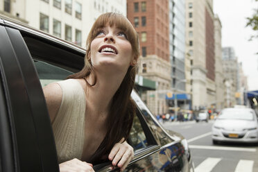 Junge Frau lehnt sich aus dem Fenster eines Taxis und schaut nach oben - ISF00432