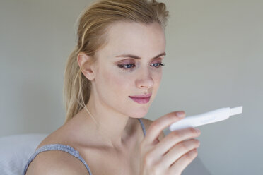 Young woman looking at pregnancy test - ISF00468