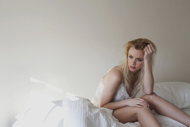 Upset young woman sitting on bed - ISF00469