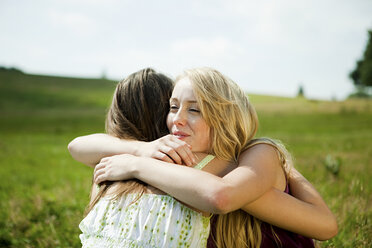 Young women embracing in a field - ISF00477