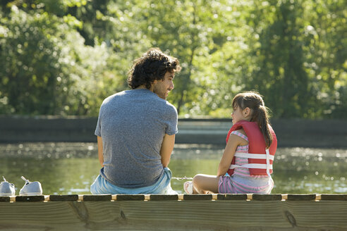 Father and daughter on jetty in lake - ISF00542