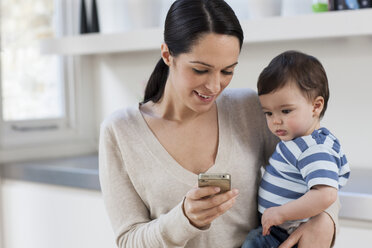 Mutter und kleiner Sohn schauen auf ihr Smartphone - ISF00555