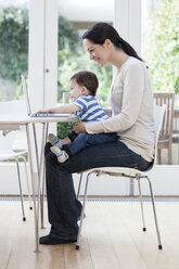 Junge Frau und ihr kleiner Sohn benutzen einen Laptop - ISF00556