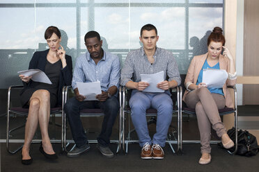 Four people sitting on chairs with documents - ISF00565