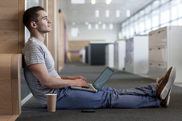Man sitting on floor using laptop - ISF00568