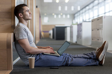 Mann sitzt auf dem Boden und benutzt einen Laptop - ISF00568