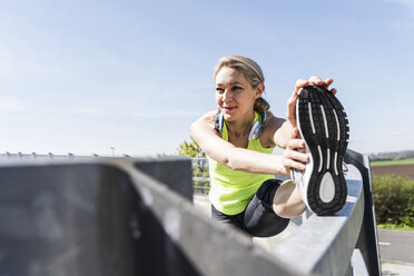 Frau joggt in der Stadt, macht eine Pause, streckt sich - UUF13595