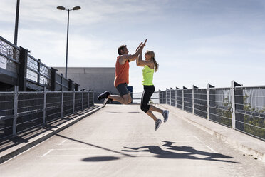 Jogging couple jumping for joy, highfiving - UUF13599