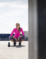 Woman training with dumbells, kneeling on ground - UUF13614