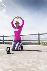 Woman training with dumbells, kneeling on ground - UUF13615