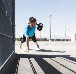 Man training with dumbells, doing one-armed plank - UUF13620