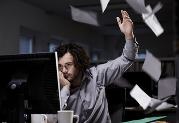 Office worker working late, throwing paper in the air - ISF00639