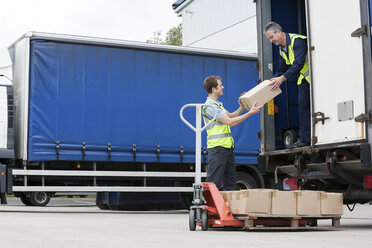 Two men unloading cardboard boxes from truck - ISF00646