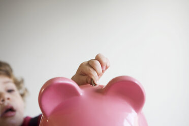 Little boy putting money in piggy bank - ISF00685