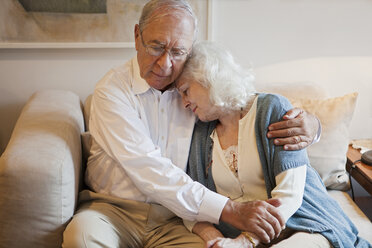 Älteres Paar umarmt sich auf dem Sofa zu Hause - ISF00729