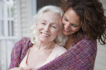 Ältere Frau und Tochter umarmen sich auf der Veranda, Porträt - ISF00733