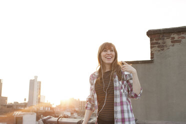 Young woman listening to music on city rooftop - ISF00755