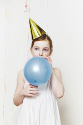 Girl in party hat, blowing up balloon - ISF00786