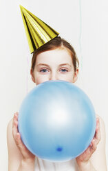 Mädchen mit Partyhut, das einen Luftballon aufbläst - ISF00787