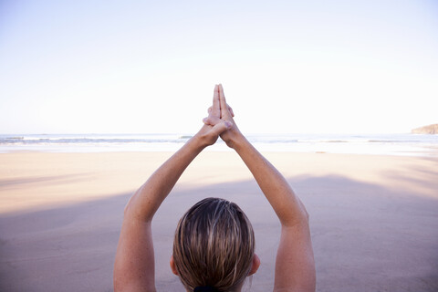 Nahaufnahme der Hände einer Frau in Baum-Yoga-Pose am Strand, lizenzfreies Stockfoto