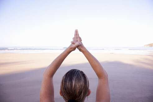 Nahaufnahme der Hände einer Frau in Baum-Yoga-Pose am Strand - ISF00794