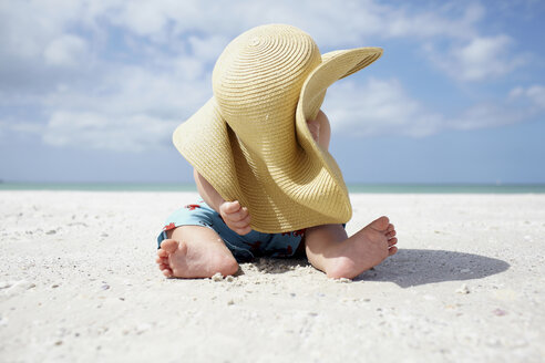 Kleiner Junge spielt mit dem Sonnenhut der Mutter am Strand - ISF00813