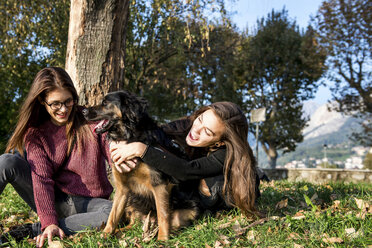 Zwei junge Frauen umarmen einen Hund, Calolziocorte, Lombardei, Italien - CUF01873