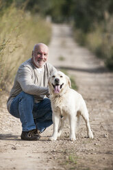 Porträt eines älteren Mannes, der neben seinem Hund hockt - CUF01883