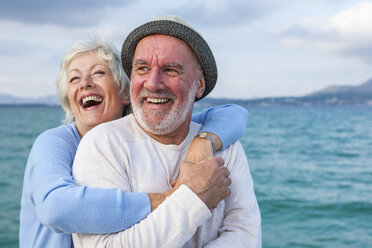 Couple hugging and laughing by seaside - CUF01935