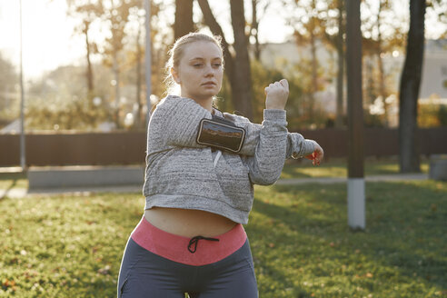 Kurvige junge Frau trainiert im Park, streckt die Arme - CUF01962