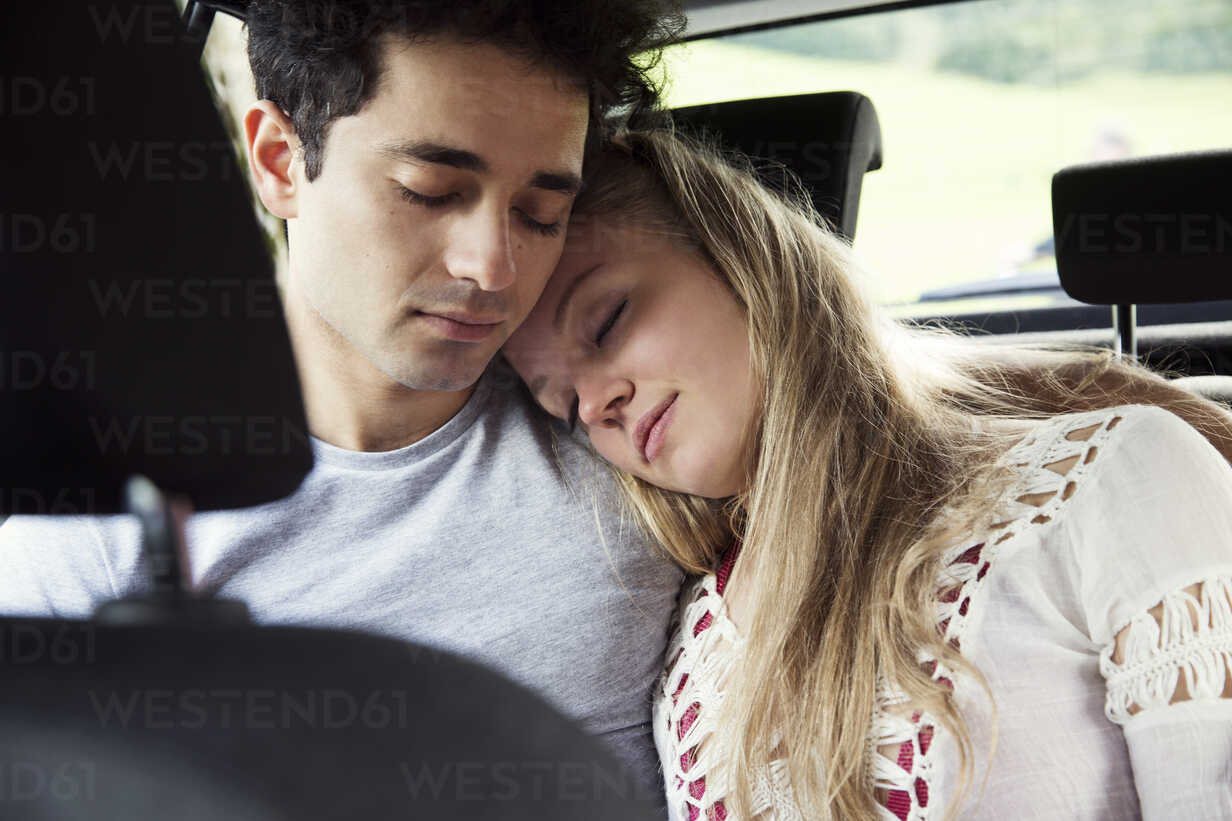 Couple in backseat of car sleeping stock photo