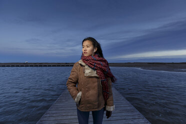 Young woman walking on pier at dusk, Tarragona, Catalonia, Spain - CUF02012