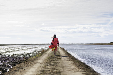 Rückansicht einer jungen asiatischen Frau in traditioneller Kleidung auf einem Feldweg am Meer, Tarragona, Katalonien, Spanien - CUF02020