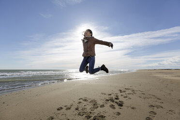 Young woman jumping mid air on beach, Tarragona, Catalonia, Spain - CUF02021